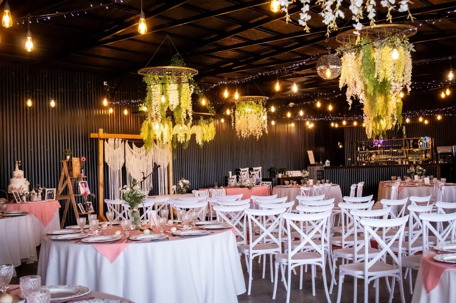 Salón preparado para una celebración con mesas, iluminación y decoración